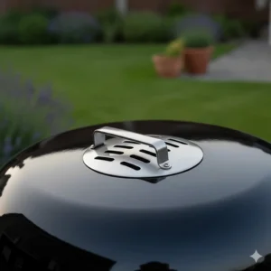 Detail of the adjustable stainless steel air vents on a charcoal BBQ grill lid for temperature control.