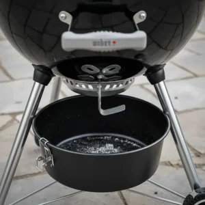 The stainless steel One-Touch cleaning system and ash catcher located at the base of the Weber Original Kettle.