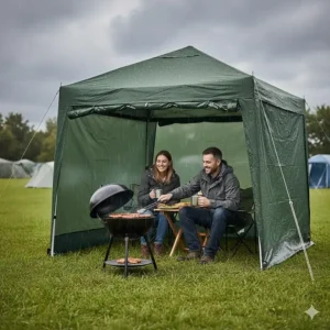 A couple sitting under a green waterproof gazebo sheltering from the rain while cooking on a charcoal BBQ.