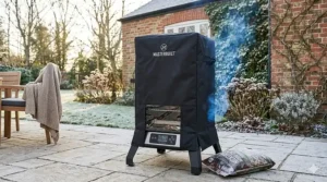 An electric smoker protected by a heavy-duty weather cover in a frosty British garden during the winter months.