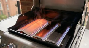 Close-up of stainless steel burners on a small gas barbecue ensuring even heat for outdoor cooking.