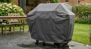 A heavy-duty waterproof cover protecting a stainless steel gas BBQ from British rain and winter weather.