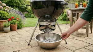 Emptying the ash catcher on a kettle BBQ, showing how easy it is to clean.