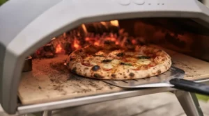 Step-by-step assembly of an affordable charcoal pizza oven on a wooden patio table, showing the main body and fuel tray.
