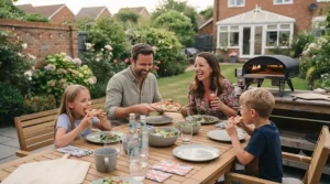 Friends and family enjoying alfresco dining in a UK back garden with a tabletop gas pizza oven.