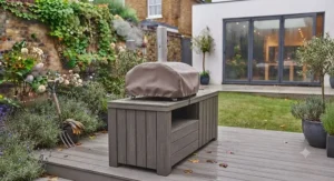 A British family gathered around a garden table enjoying homemade pizza cooked in an outdoor electric oven.