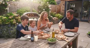 Family gathering around a garden table enjoying homemade wood-fired pizza cooked in a dual fuel oven.