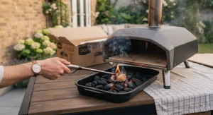 Glowing charcoal briquettes burning inside a stainless steel pizza oven firebox.