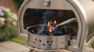 Adding lumpwood charcoal to the fuel basket of a portable pizza oven to reach high cooking temperatures.
