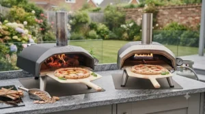 Essential accessories laid out next to a budget pizza oven, including a metal pizza peel and cordierite baking stone.