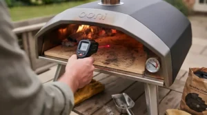 A compact, lightweight charcoal pizza oven positioned on a small garden table, demonstrating its suitability for British patios and balconies.