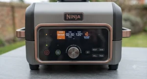 A portable USB-powered mini fan plugged in next to a smartphone on a bedroom desk.