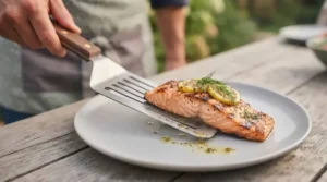 Slotted barbecue spatula draining excess oil from freshly grilled salmon
